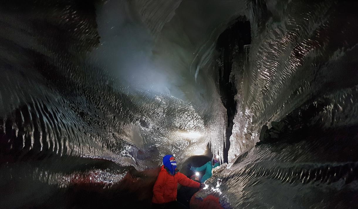 Guests exploring an ice cave with hedlamps on