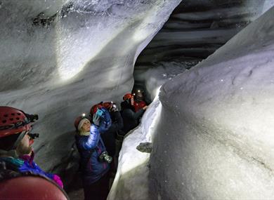 Several people walking inside an ice cave.