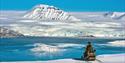 En guide som tar en pause på snøscooteren og ser ut over landskapet