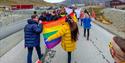 Persons walking in a parade for Longyearbyen Pride with flags