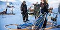 A guide showing guests how to drive a dog sled
