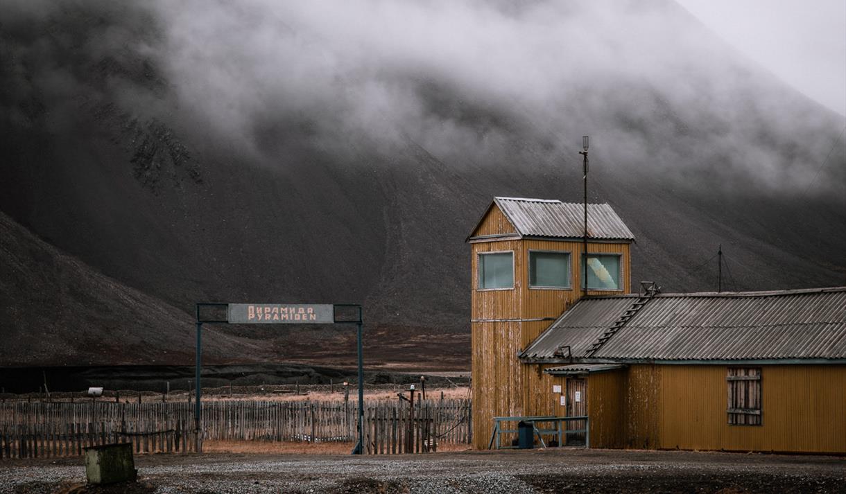 An abandoned building in Pyramiden with fog and a mountain in the background
