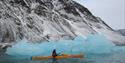 A guest paddling alongside a small iceberg