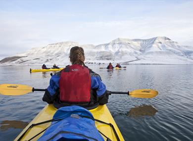 People in kayaking in Adventfjorden. Hiortfjellet is seen in the background 