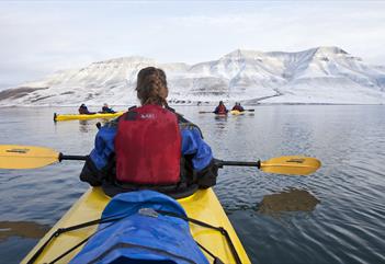 People in kayaking in Adventfjorden. Hiortfjellet is seen in the background