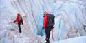 Two persons tied into a rope while hiking on a glacier