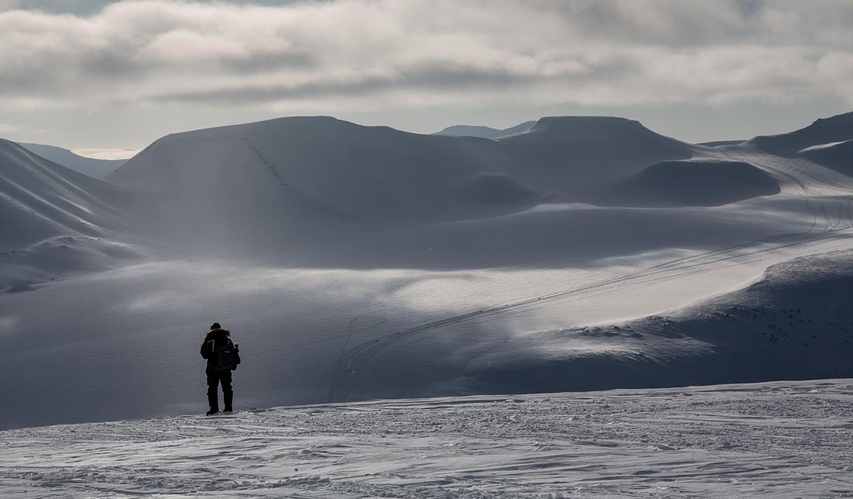 En person som står for seg selv og ser utover et snødekt landskap