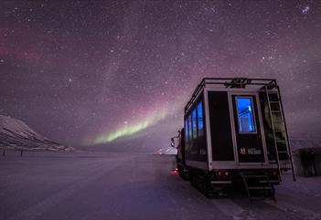 Northern Lights shining in the skies above a snowcat