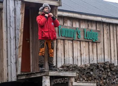 A man standing in front of Tommy's Lodge
