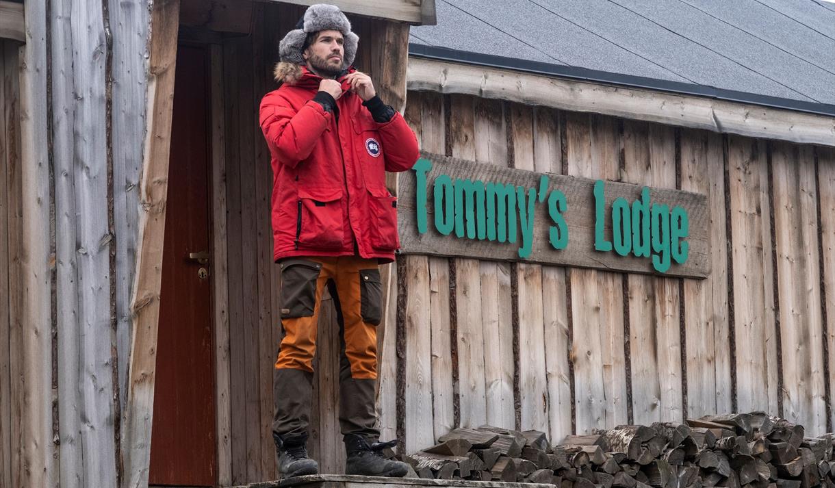 En mann som står på trappa foran Tommy's Lodge