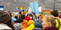 Personer som går i en parade for Longyearbyen Pride med et banner og flagg