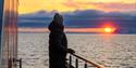 Person som ser på solnedgang fra en båt