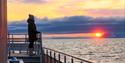 Person som ser på solnedgangen fra en båt