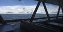 Utsikt mot en isbre og en fjord fra innsiden av båten MS Bard sine panoramavinduer