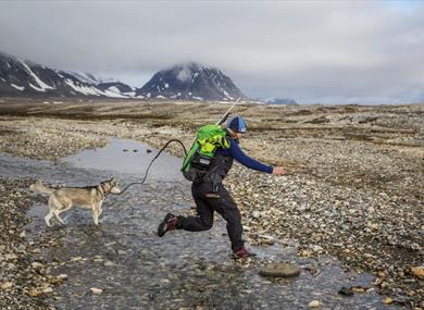 Guide with dog, jumping over a riverbed