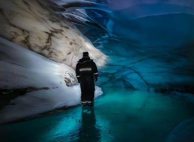Person standing inside the blue icecave