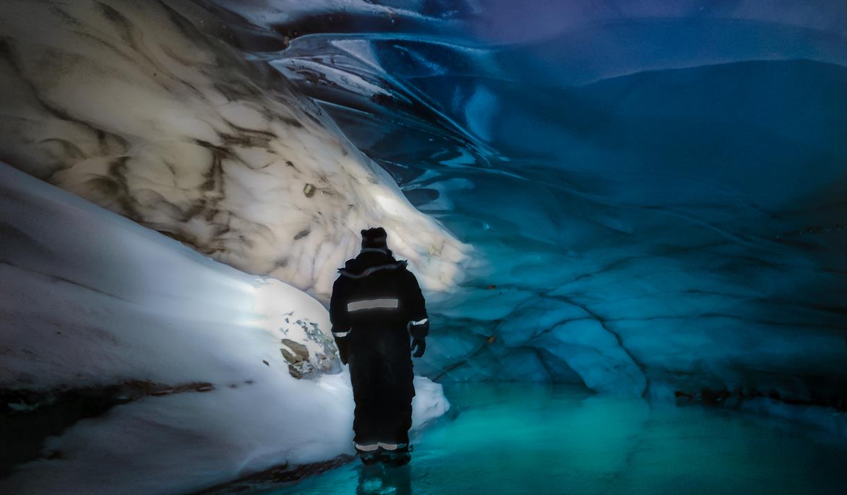 Person standing inside the blue icecave