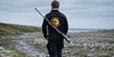 En guide med Svalbard Wildlife Expeditions sin logo og en rifle på ryggen som går på tur