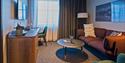 Et hotellrom med en sofa, kaffebord og arbeidspult
