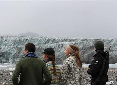 Four people looking out towards the glacier in the background.