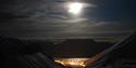 Longyearbyen i enden av dalen. Måneskinnet lyser opp fjellene rundt.