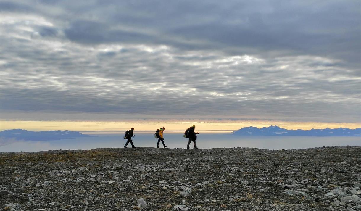 Tre personer vandrer langs kysten