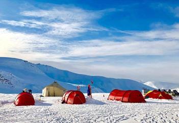 Tent camp in a sunlit winter landscape