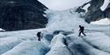 Two persons tied together with a rope hiking across a glacier
