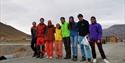A group of friends that have dressed up to look like a rainbow while standing together