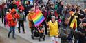 Persons walking in a parade for Longyearbyen Pride with flags