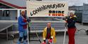 Three persons with a banner for Longyearbyen Pride