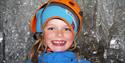 Glad og smilende barn med hjelm, inne i isgrotta