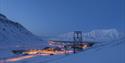 Landscape photo of Longyearbyen seen from above in blue winter light with snow-covered mountains in the background