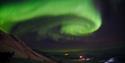 A whirling stream of northern lights in the skies above a valley