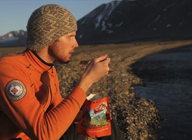 A person sitting on a beach eating an expedition lunch