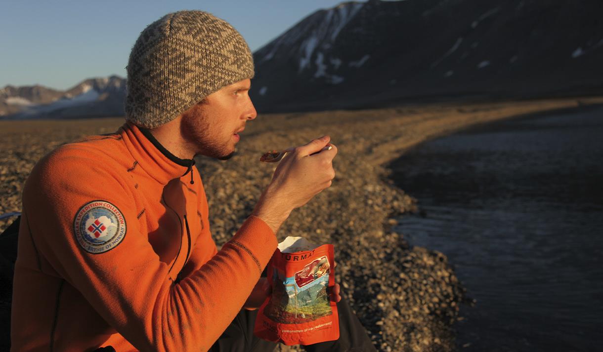 A person sitting on a beach eating an expedition lunch