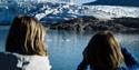 To personer på en båt som ser ut over en fjord mot en sel som ligger på et lite isflak