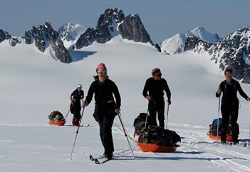 En turgruppe som drar pulker på ski