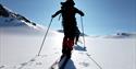 En person som går på ski med sola foran seg