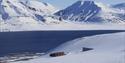 Svalbard Globale Frøhvelv i lyse snødekte omgivelser med en fjord og tilsnødde fjell i bakgrunnen