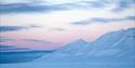 Snow-covered mountains and a partially cloudy pink sky