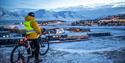 En gjest på sykkel som ser ut over bygningene i Longyearbyen fra et utsiktspunkt