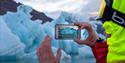 A person taking photos of icebergs