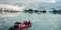 En båt med gjester om bord som seiler foran en isbre