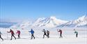 Deltakere på Svalbard Skimaraton i skiløypa med fjell i bakgrunnen