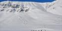Deltakere på Svalbard Skimaraton i skiløypa med fjell i bakgrunnen