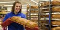 An employee in Svalbardbutikken preparing freshly made loaves of bread for sale