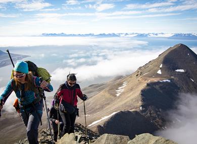 Persons hiking above the clouds on the top of hiortfjellet 