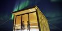 Two persons in the sauna at Isfjord Radio Adventure Hotel with northern lights shining in the sky above.
