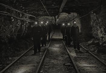 A group of guests with head lamps and helmets on, walking through a mine passage on a guided tour